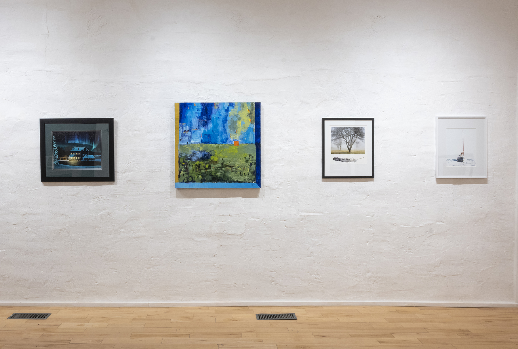 Paintings and photographs hung on gallery wall