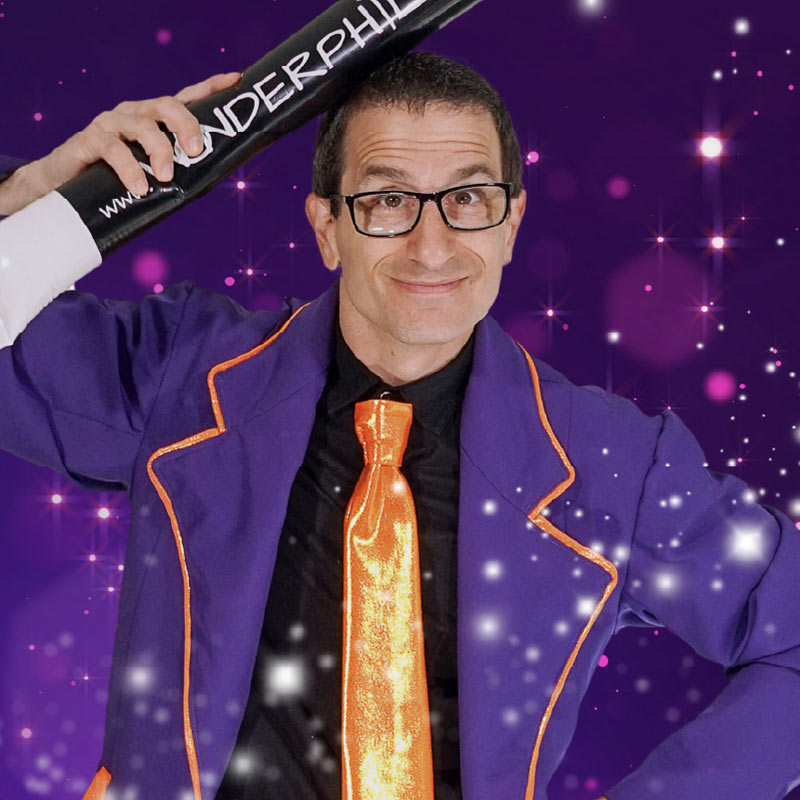 A photo of Wonder Phil holding a large magic wand above his head.