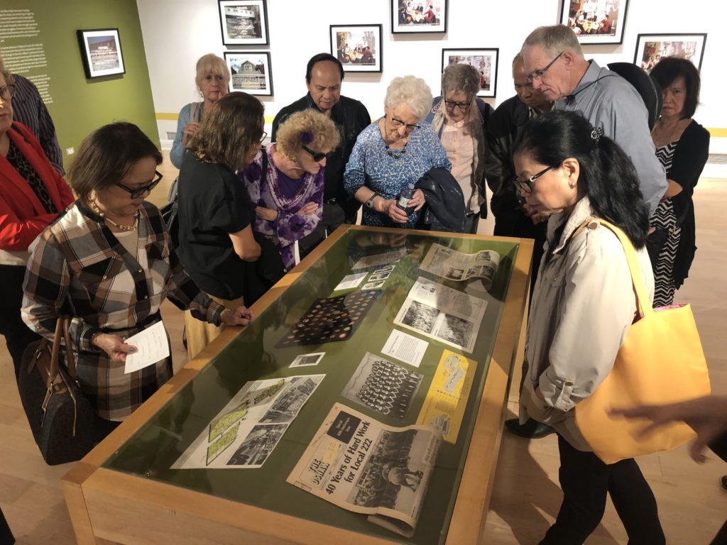 A group of people look over a glass display of photographs
