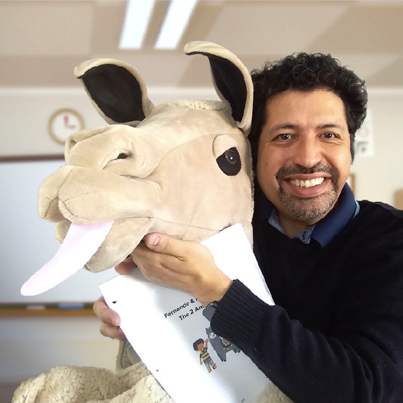 A photo of the creator of Fernando and his Llama, holding a large llama puppet.